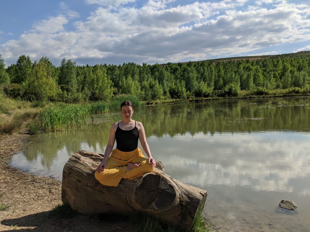frau meditiert am see